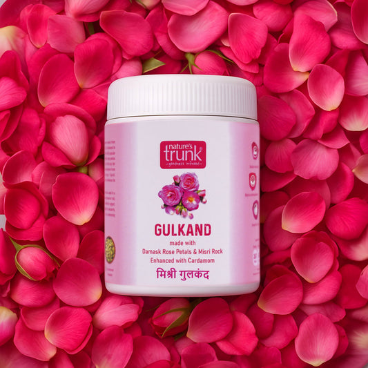Nature's Trunk gulkand jar surrounded by pink rose petals, showcasing Damask rose petal preserve with cardamom